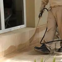 General pest control technician spraying exterior perimeter around a home in Richmond, VA