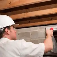 Termite inspection technician checking a basement wall and framing for termite activity in Richmond, VA