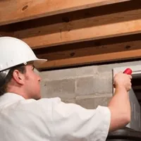 Termite inspection technician checking a basement wall and framing for termite activity in Richmond, VA